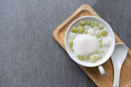 Pandan Thai glutinous rice balls (Bua Loi) in white bowl on table,Boiled egg.の写真素材
