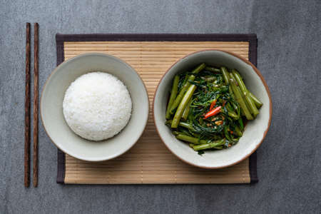 Fried morning glory with rice in gray bowl on table.の写真素材