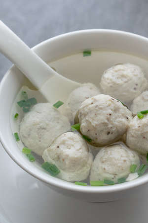 Chicken ball soup with scallion in white bowl on table.の写真素材