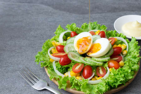 Healthy vegetables salad with boiled egg in wooden dish on table for vegetarian.の写真素材