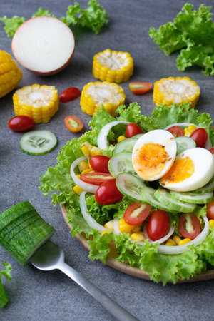 Healthy vegetables salad with boiled egg in wooden dish on table for vegetarian.の写真素材