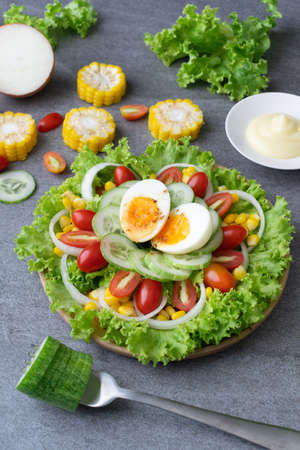 Healthy vegetables salad with boiled egg in wooden dish on table for vegetarian.の写真素材
