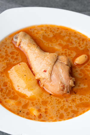 Massaman curry with chicken drumstick or leg and potato in white dish on table.の写真素材