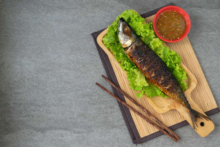 Grilled Saba Fish in wooden dish with seafood sauce on table.の写真素材