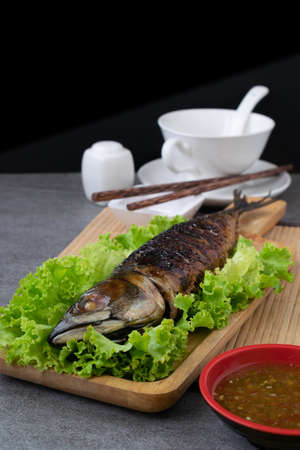 Grilled Saba Fish in wooden dish with seafood sauce on table.の写真素材