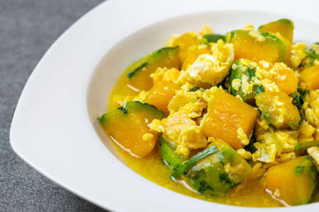Fried pumpkin with egg for children in white dish on concrete table.の写真素材