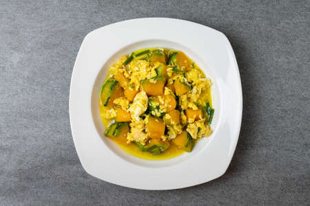 Fried pumpkin with egg for children in white dish on concrete table.の写真素材