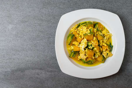 Fried pumpkin with egg for children in white dish on concrete table.の写真素材