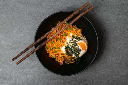 Drunken spicy noodles in black bowl with Onsen egg on the concrete table.の写真素材