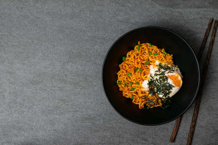 Drunken spicy noodles in black bowl with Onsen egg on the concrete table.の写真素材