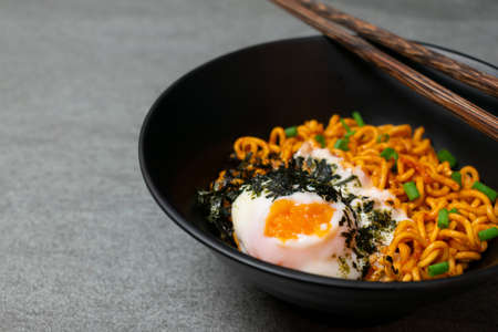 Drunken spicy noodles in black bowl with Onsen egg on the concrete table.の写真素材