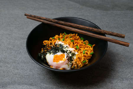 Drunken spicy noodles in black bowl with Onsen egg on the concrete table.の写真素材