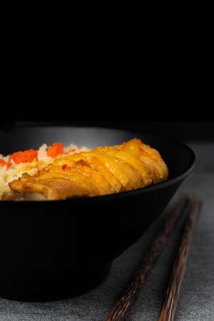 Fried rice with roast chicken and carrot in Korean style in black bowl on table.の写真素材
