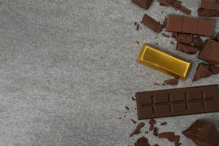 Broken chocolate with small piece and gold on tile table.の写真素材