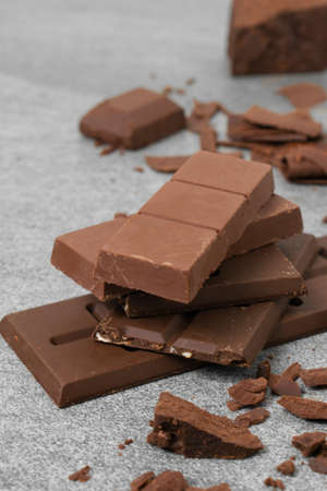 Broken chocolate with small piece on tile table.