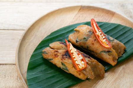 Grilled fish with curry paste and coconut milk on banana leaf in wooden dish,Thai food.の写真素材