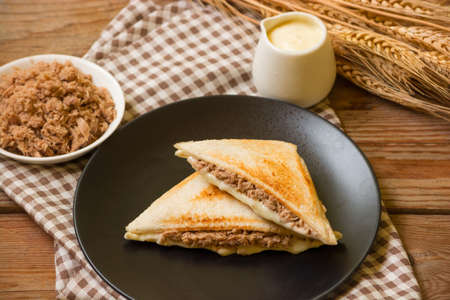 Sandwich stuffed with salad sauce and dried Tuna in black dish on wooden table.の写真素材