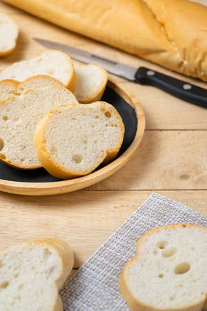 Sliced baguettes on wooden dish with knife on the wooden table.の写真素材