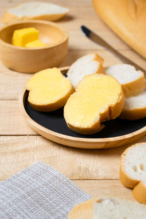 Sliced baguettes on wooden dish with butter on the wooden table.の写真素材