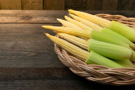 Baby corn in basket on wooden table background.の写真素材