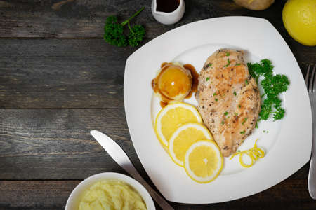 Baked chicken breast with lemon for fresh in white dish on wooden table.の写真素材