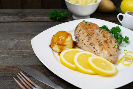 Baked chicken breast with lemon for fresh in white dish on wooden table.の写真素材