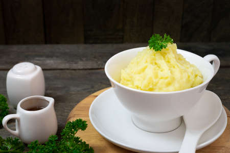 Mashed potatoes in white bowl or glass with parsley on wooden table.の写真素材