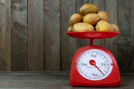Potatoes on red scales on old wooden background.の写真素材