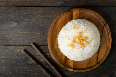 Rice with fried garlic in wooden dish on wooden table.の写真素材