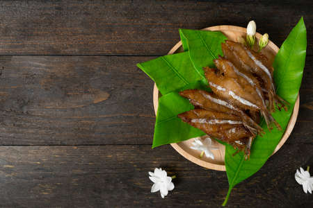 Fried dried fish on mango leaf in wooden dish on wooden table.の写真素材