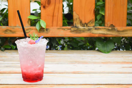 Strawberry Italian soda with butterfly pea flowers in plastic glass on wooden table.の写真素材