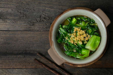Fried Bok choy in oyster sauce with fried garlic in bowl on wooden table.の写真素材
