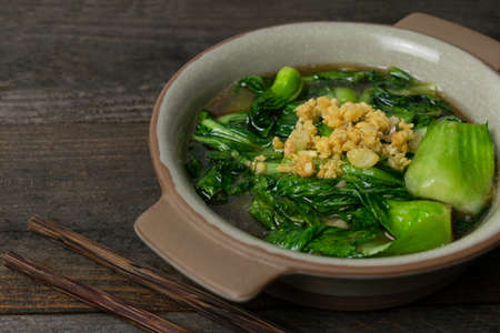 Fried Bok choy in oyster sauce with fried garlic in bowl on wooden table.の写真素材