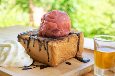 Honey toast in wooden tray on wooden table on nature background.の写真素材