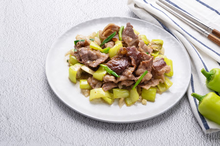 Stir fried green pepper with brisket sliced in white dish on concrete table.の写真素材