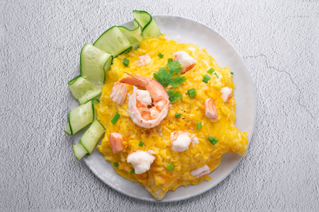 Omelet and shrimp on rice with cucumber in gray dish on concrete table. (Scrambled egg)の写真素材