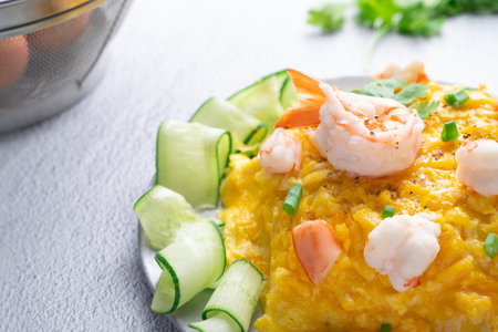Omelet and shrimp on rice with cucumber in gray dish on concrete table. (Scrambled egg)の写真素材