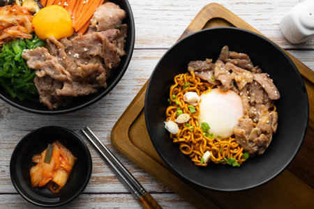 Korean instant noodle with stir fried brisket and onsen egg in black bowl on wooden table.の写真素材
