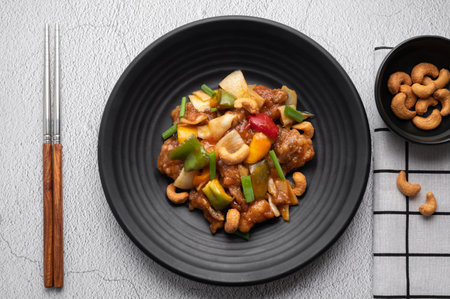 Stir fried chicken with cashew nuts in black dish on concrete table.の写真素材
