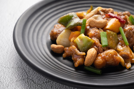 Stir fried chicken with cashew nuts in black dish on concrete table.の写真素材