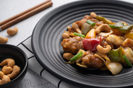 Stir fried chicken with cashew nuts in black dish on concrete table.の写真素材