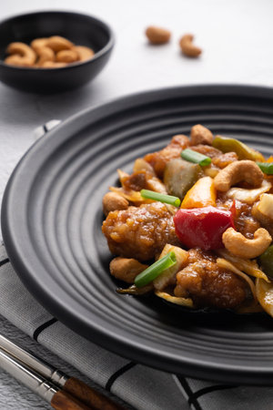 Stir fried chicken with cashew nuts in black dish on concrete table.の写真素材