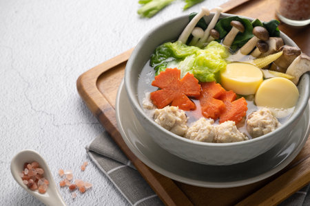 Vegetables soup with chicken ball and egg tofu in gray bowl on concrete table.の写真素材