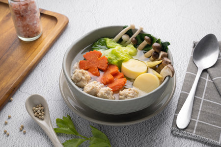 Vegetables soup with chicken ball and egg tofu in gray bowl on concrete table.の写真素材