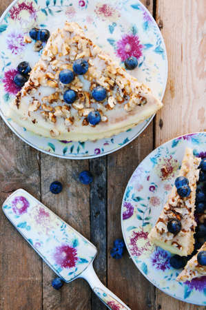 Slice of delicious cake with fresh blueberry on wooden backgroup. Piece of blueberry cake, piece of cake on white plate with blueberry, breakfast, food and drink, knife and fork. Cup of coffe.の写真素材