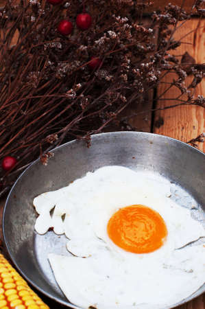 Fried eggs in a frying pan on wooden background. Breakfast. Healthy food. Fried eggs. Fried egg on a pan. Rustic food style. Ripe corn. Food and drink.の写真素材
