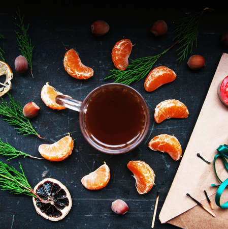 Winter decoration. Composition on wood background. Hot tea, candles, cut grapefruit. Christmas. Christmas mood. Christmas spirit. Fir branches. Tangerine slices. Conesの写真素材