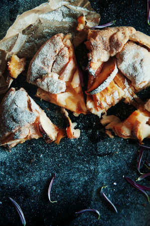 Pear pie sprinkled with powdered sugar on a black background. Beautiful chocolate pear tart in section. Delicious dessert for breakfast. Rustic dark food style.の写真素材