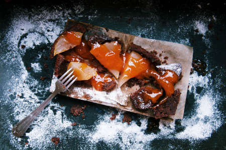 Pear pie sprinkled with powdered sugar on a black background. Beautiful chocolate pear tart in...