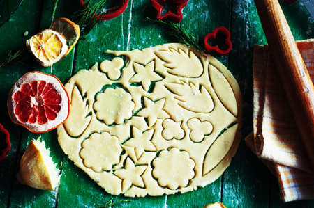 Process of baking cookies at home. Fresh dough ready for baking on rustic green wooden background. Dough ingredients and decorations aroundの写真素材